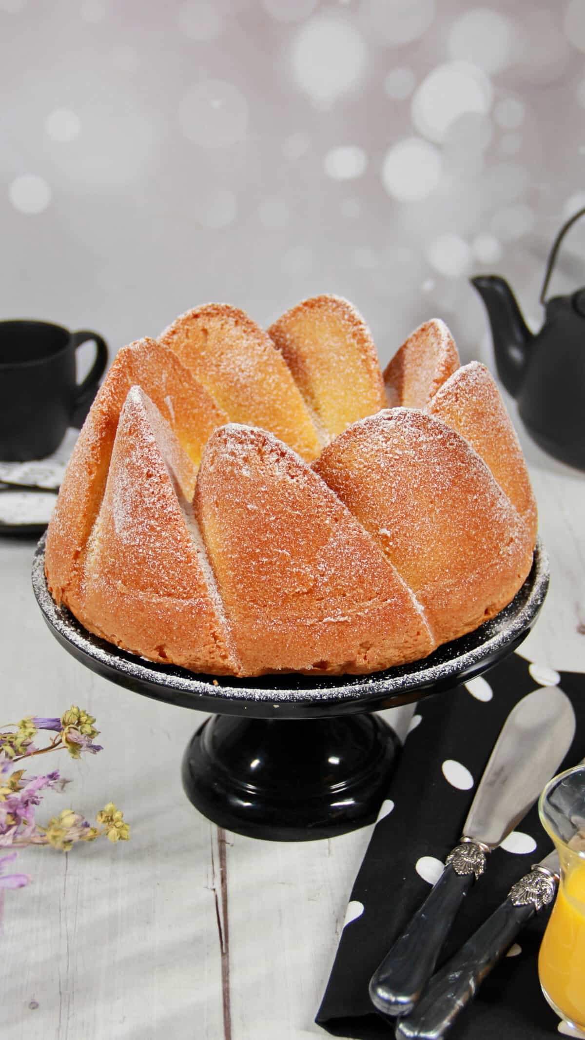 Ein Eierlikörkuchen auf einem runden, schwarzen Kuchenständer.