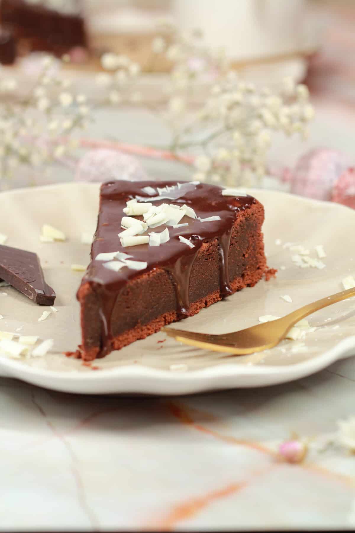 Ein Stück Schokoladenkuchen mit weissen Schoko raspeln darauf.