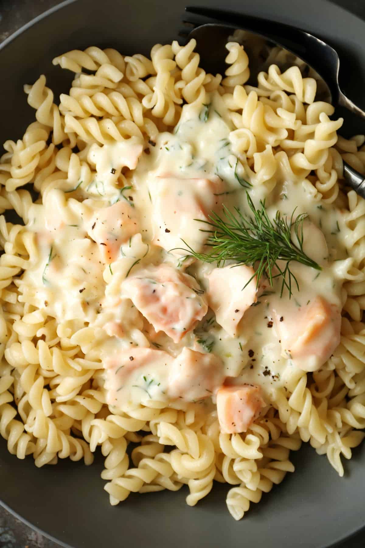 A close-up of a plate of pasta with salmon and cream sauce.