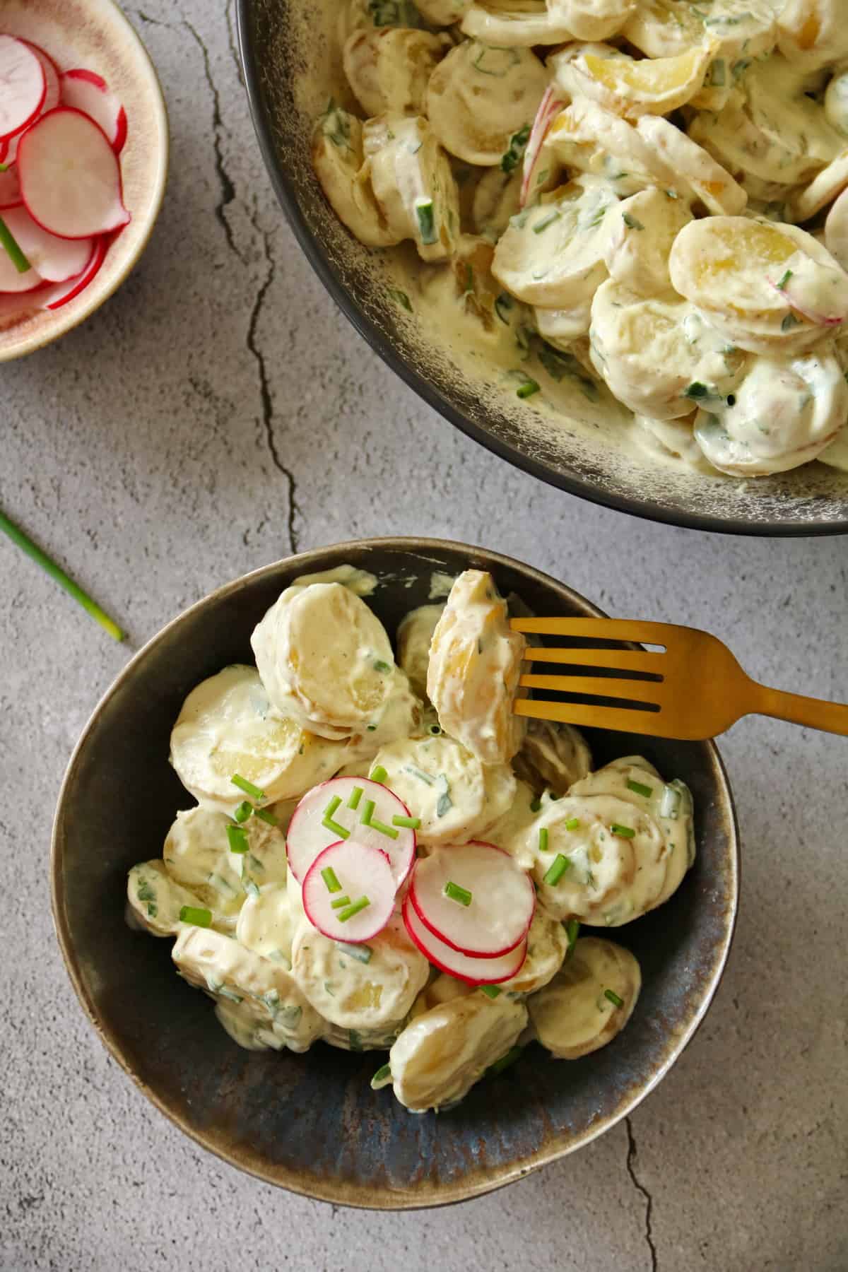 A bowl of potato salad. Top with a small bowl of radishes and a bowl of potato salad
