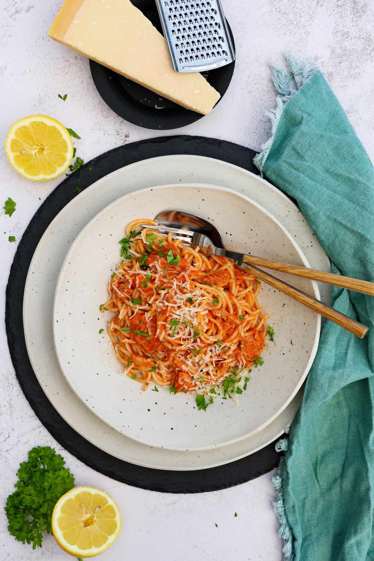 A white plate of spaghetti with tuna and tomato sauce.