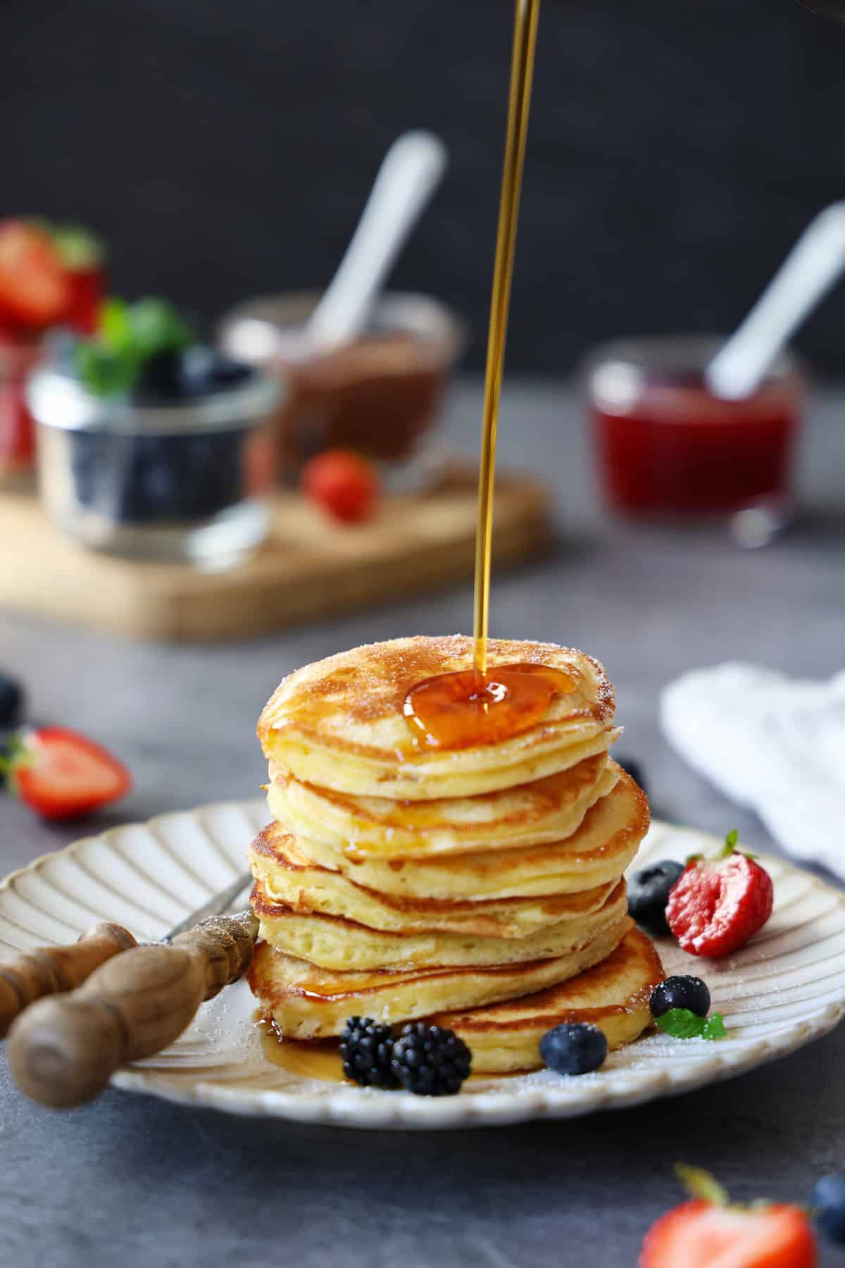 Sirup läuft auf einen Stapel Pancakes auf einem Teller.