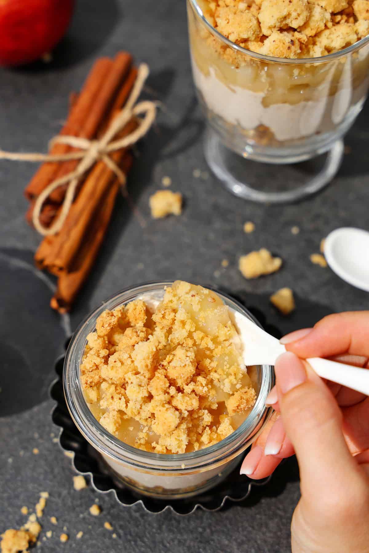 Zwei Gläser mit Apfel-Quark-Dessert mit Streuseln.