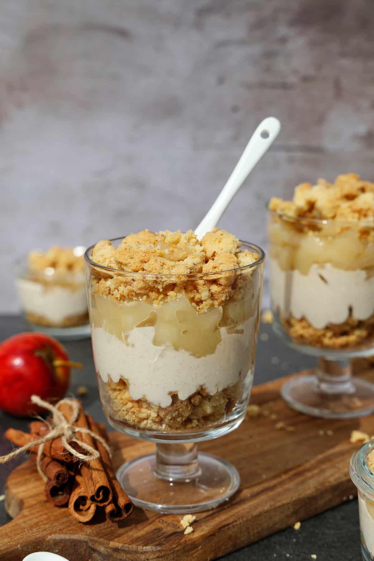 Mehrere Gläser mit Apfel-Quark-Dessert mit Streuseln.