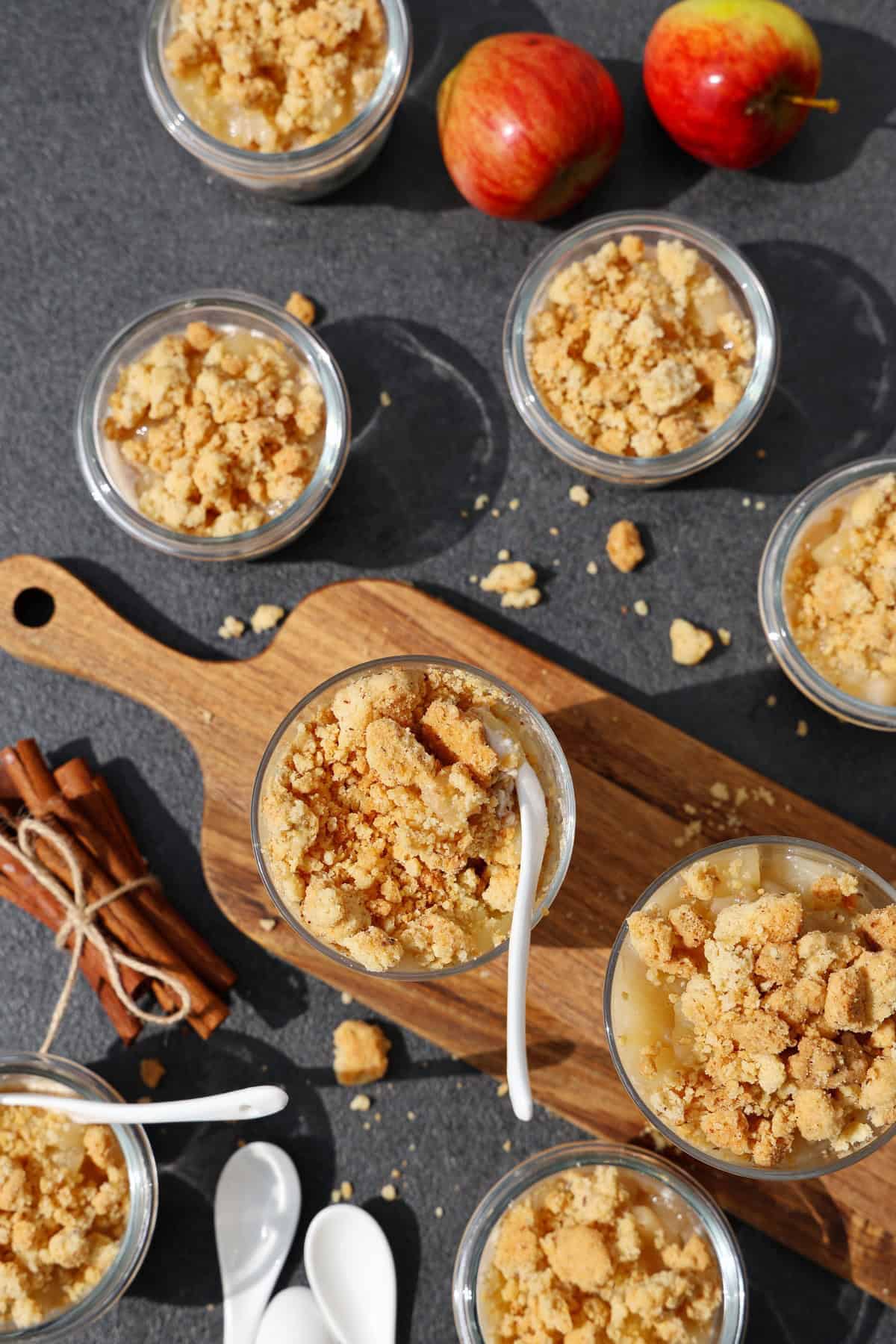 Mehrere Gläser mit Apfel-Quark-Dessert mit Streuseln von oben fotografiert.