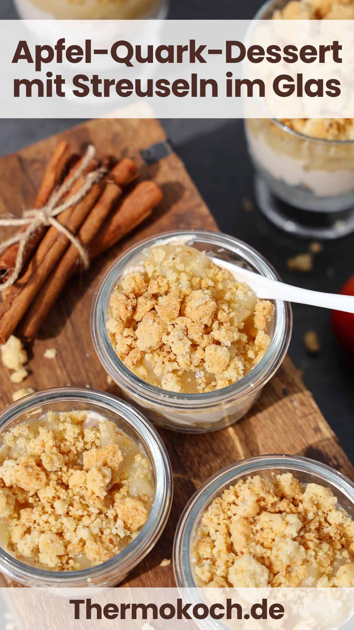 Mehrere dekorativ angerichtete Gläser mit Apfel-Quark-Dessert mit Streuseln. Daneben einige Zimtstangen.