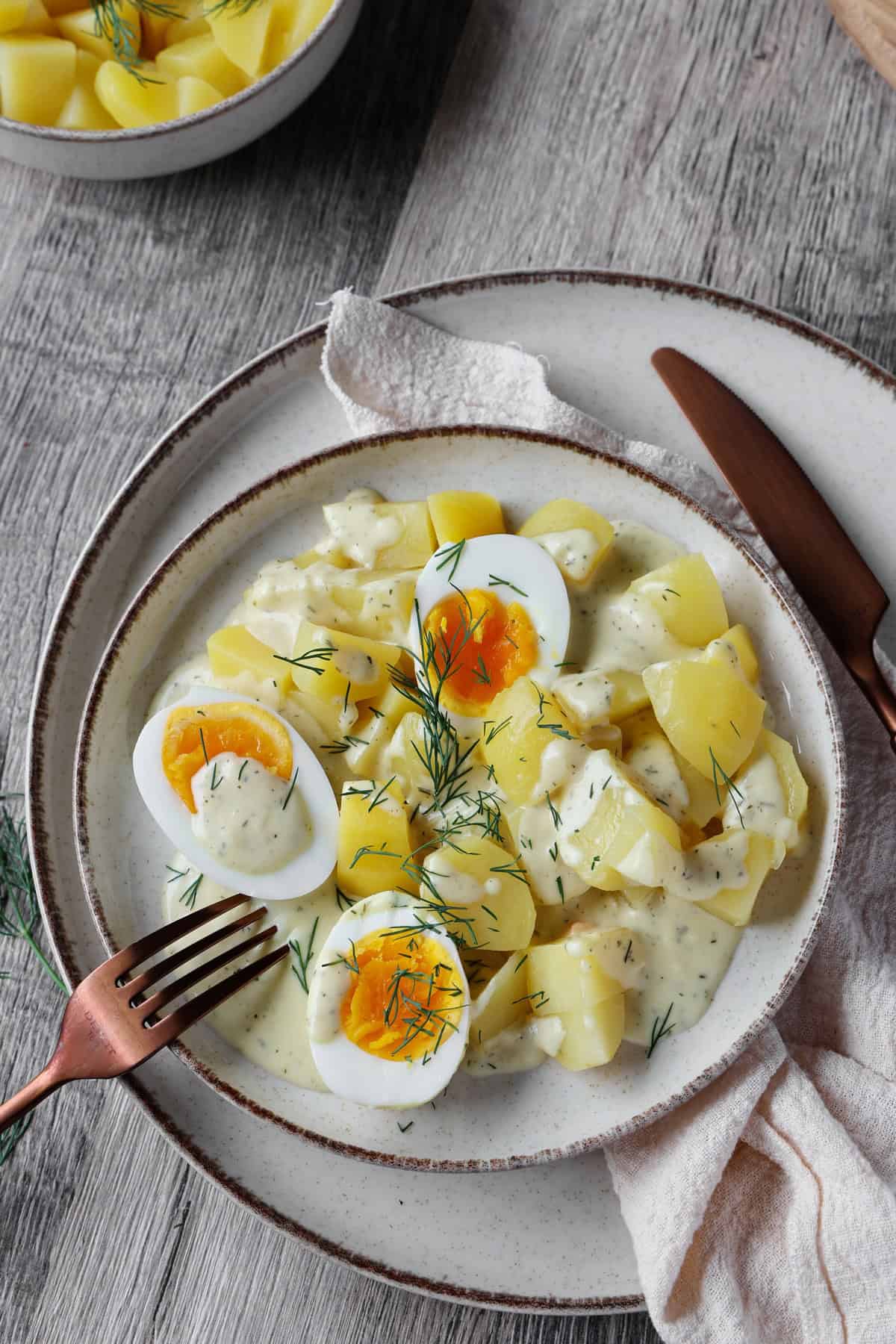 Ein Teller mit Eiern in Senfsoße und Kartoffeln.