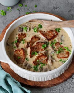 Eine weiße Schüssel mit Jägertopf mit Schweinefilet und Champignons.