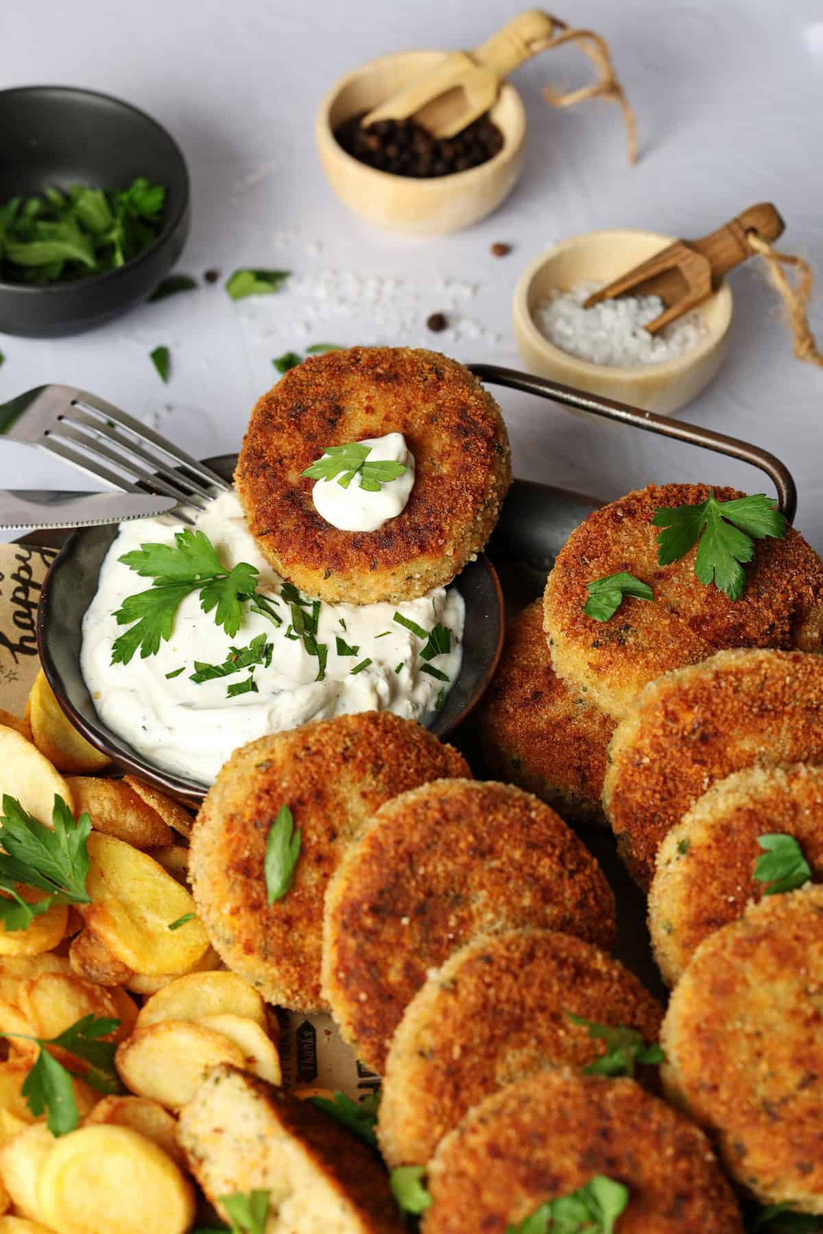 Eine Nahaufnahme von einem Teller mit Gemüsefrikadellen, Pommes und einem Dip.