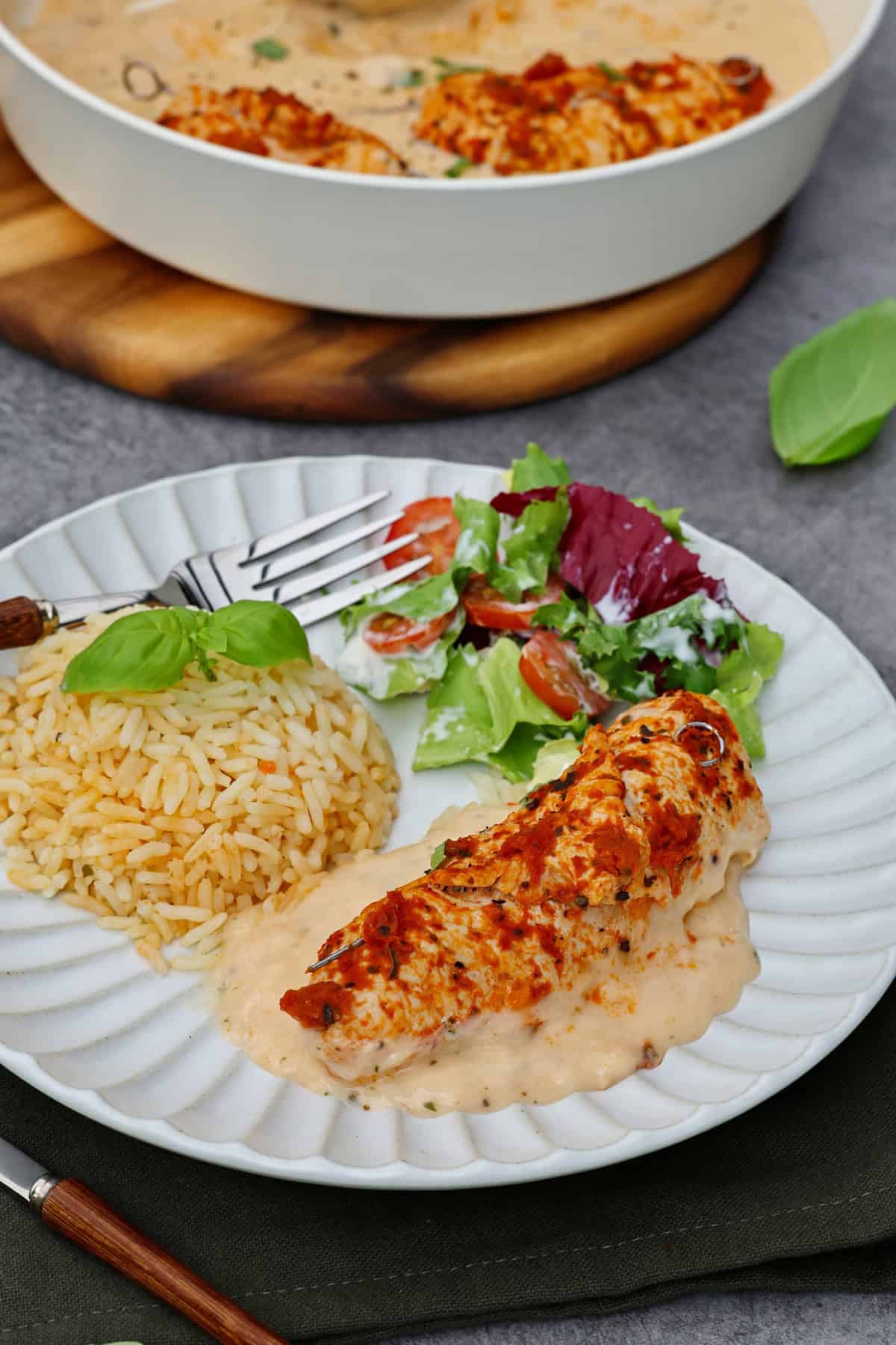 Ein Teller mit Putenrouladen mit Pesto, Reis und Salat.