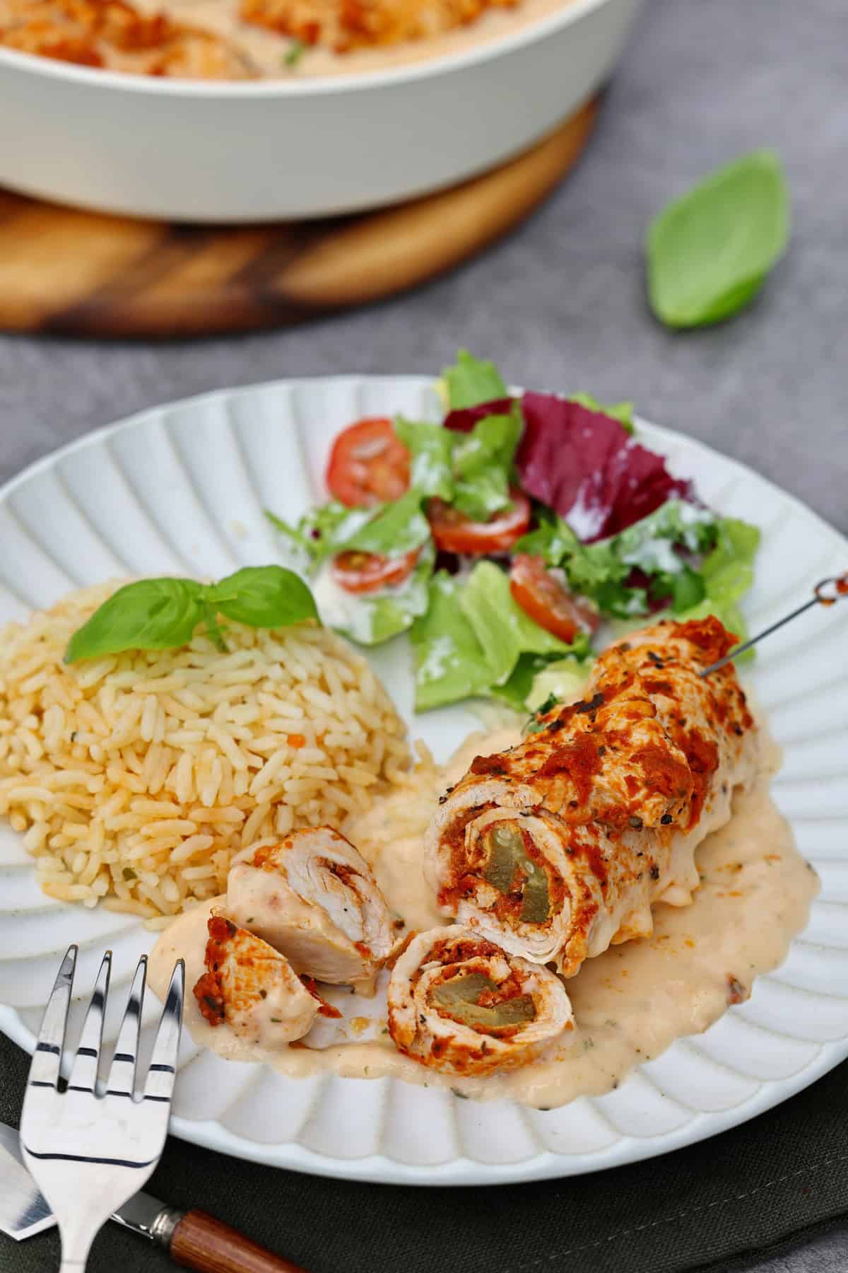 Ein Teller mit Putenrouladen mit Pesto, Reis und Salat.