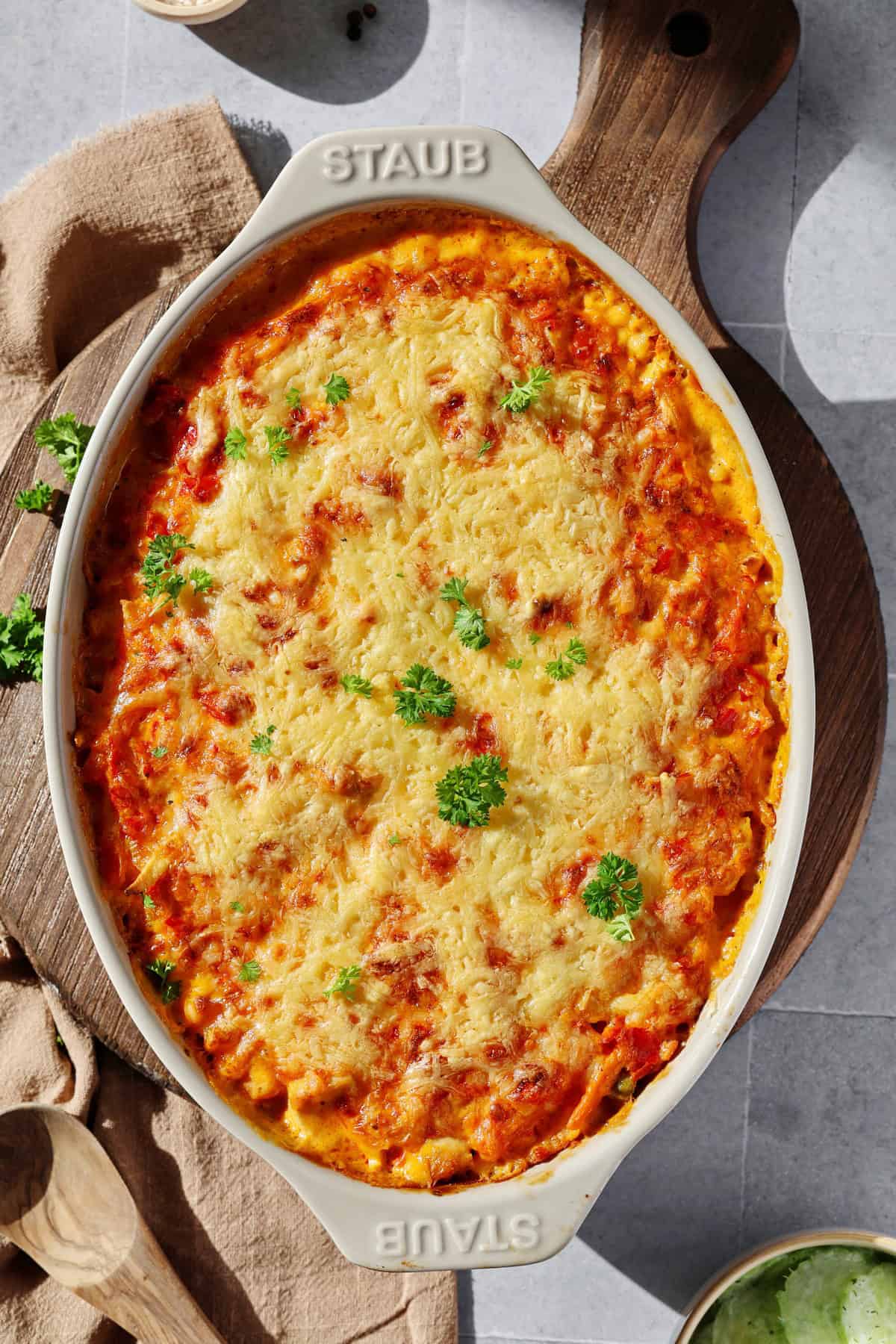 Eine ovalförmige, hellgraue Auflaufform mit einem Spätzle-Auflauf mit Hähnchen.