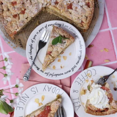 Mehrere Stücke Rhabarber-Streuselkuchen auf Kuchentellern.
