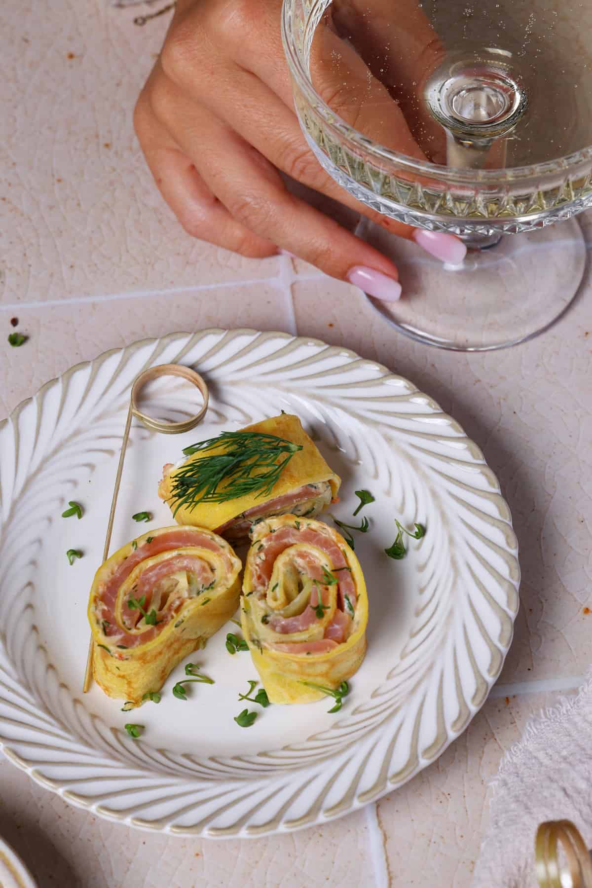 A plate filled with salmon crêpe pinwheels made with dill cream cheese.