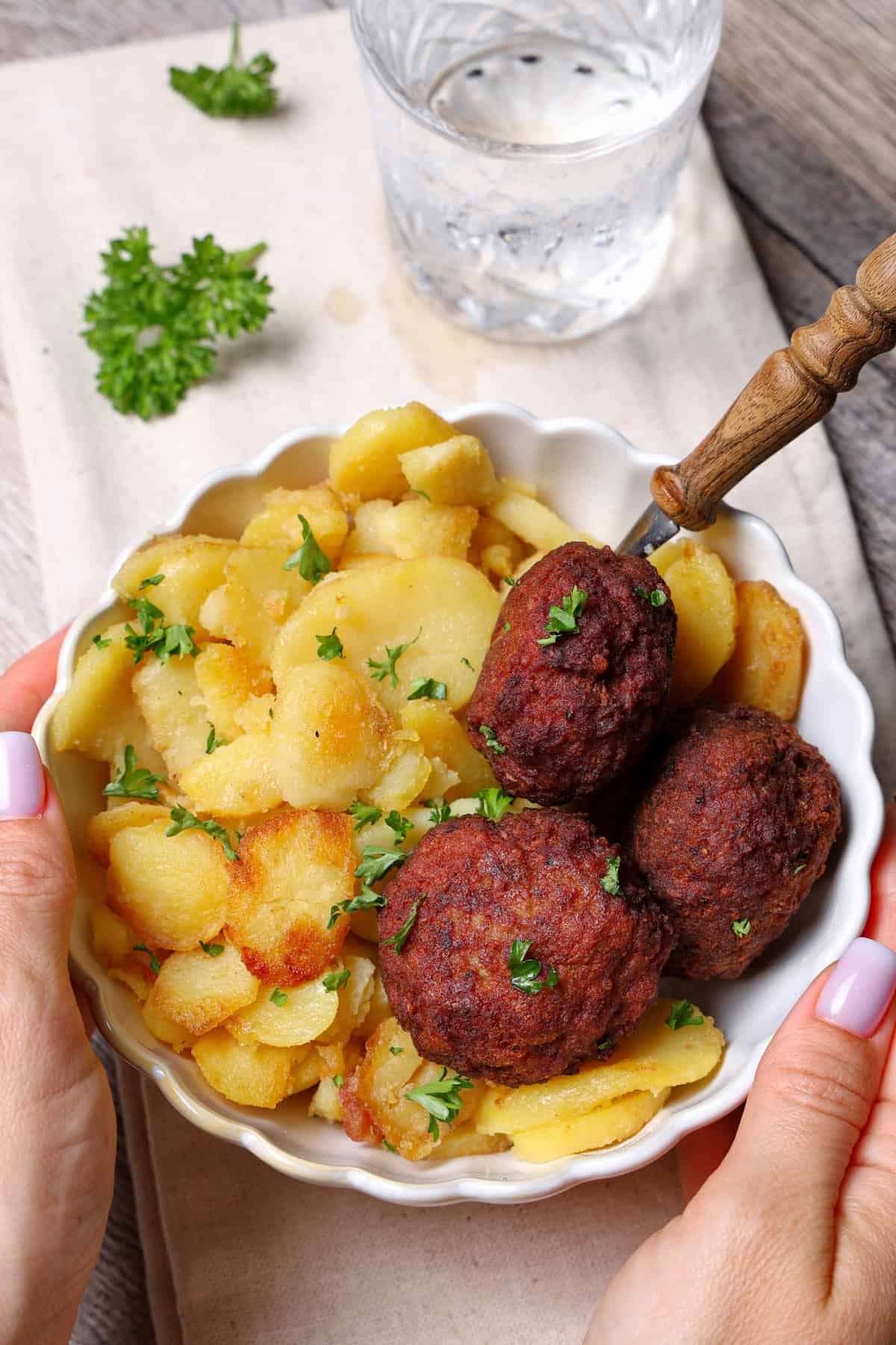 A white Schgale with fried potatoes and meatballs.