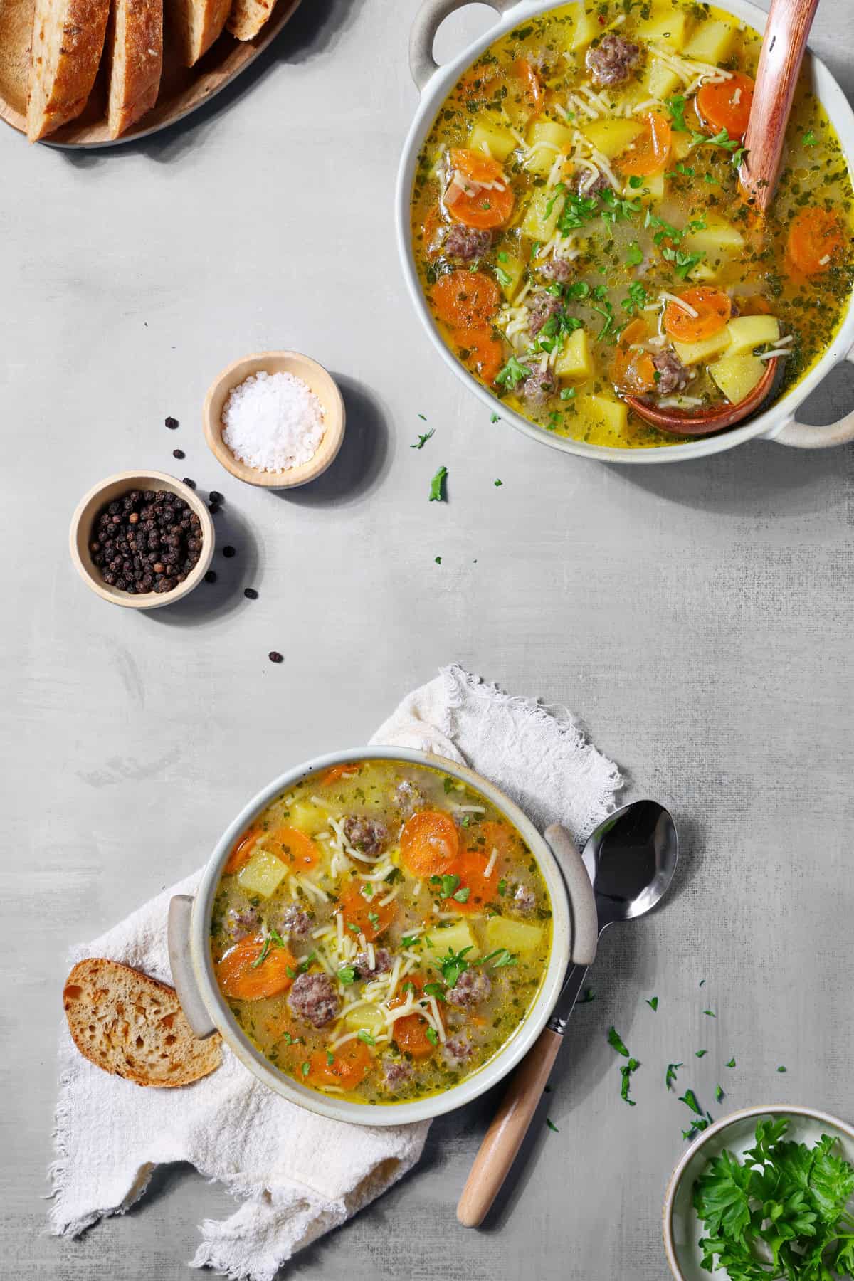 Two white soup bowls filled with meatball soup.