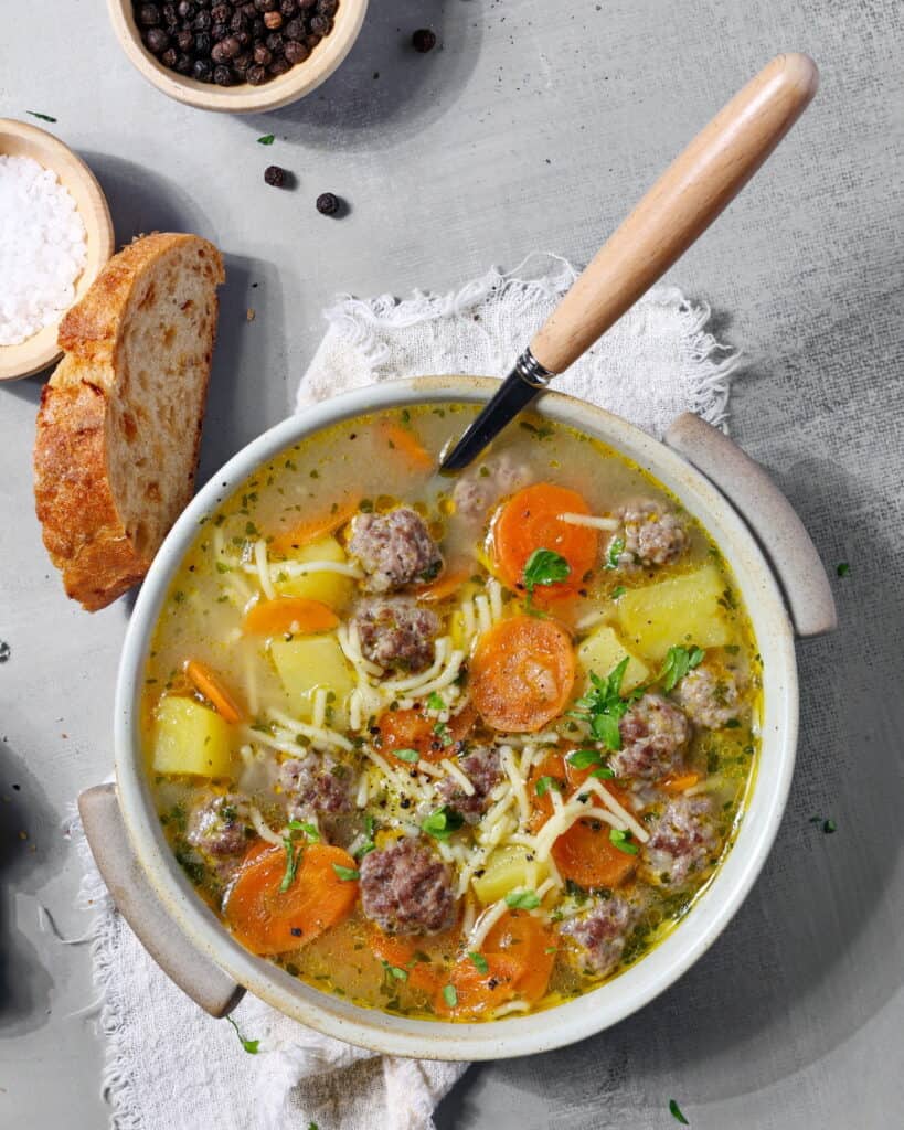 Eine Schalte mit Frikadellen-Suppe. Darüber eine Scheibe Brot.