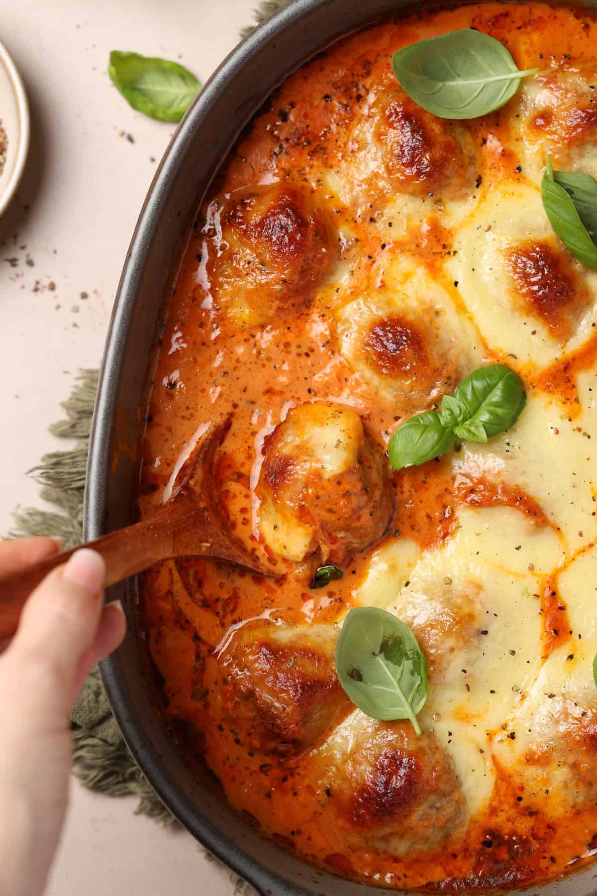 A close-up of a casserole dish with cheesy Tuscan meatballs.