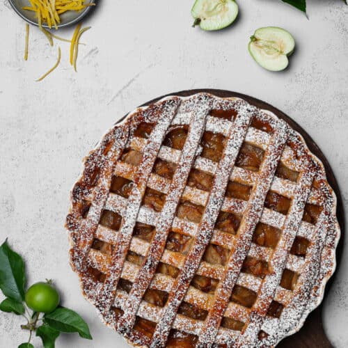 Ein Apple Pie auf einem runden Holztablett. Darüber Deko.