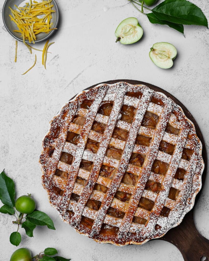 Ein Apple Pie auf einem runden Holztablett. Darüber Deko.