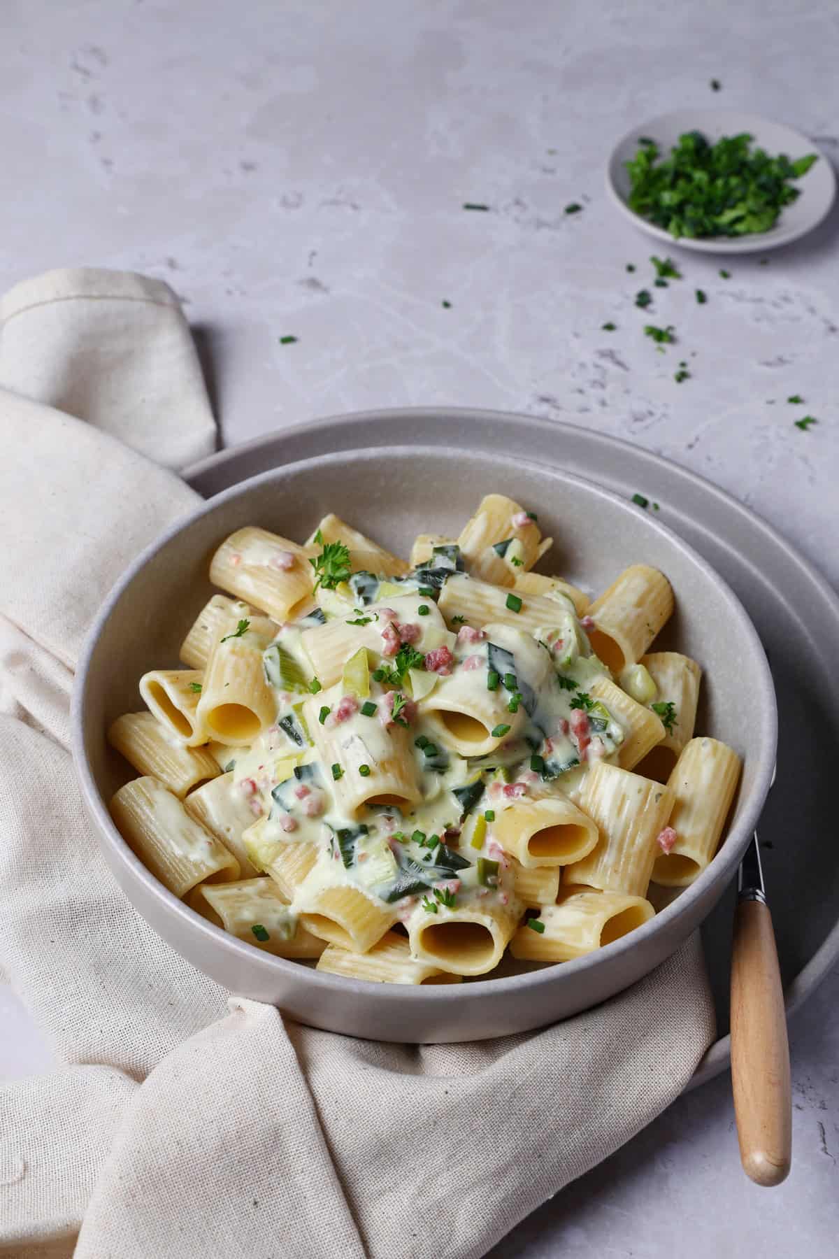 A deep gray bowl filled with cheesy leek pasta.