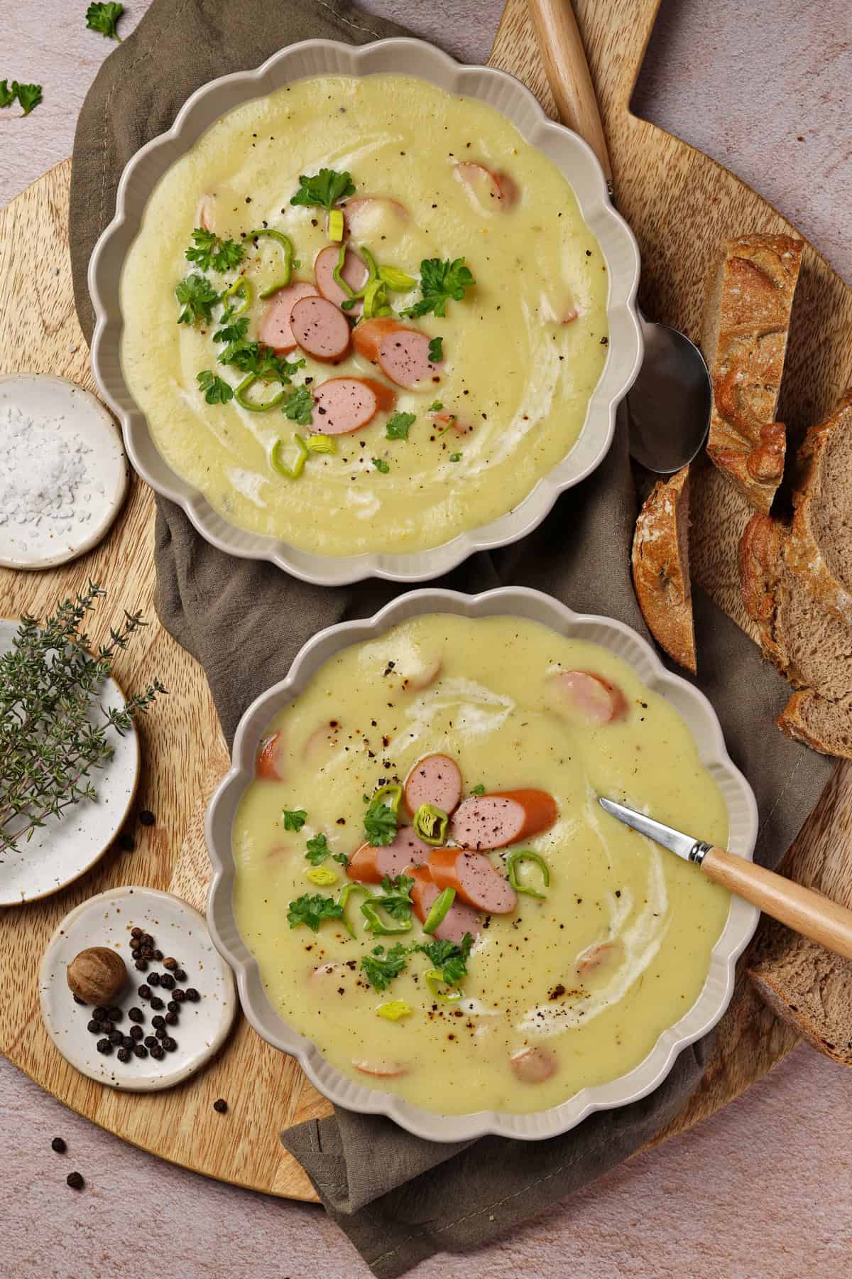 Zwei Teller mit Kartoffel-Pastinaken-Suppe mit Wienerle.