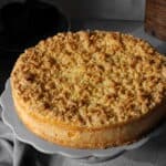 Ein Mandarinen-Schmand-Streuselkuchen auf einem runden Serviertablett.