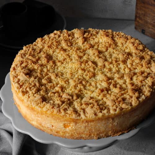 Ein Mandarinen-Schmand-Streuselkuchen auf einem runden Serviertablett.