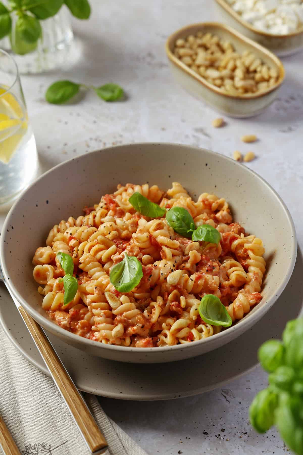 A gray bowl filled with pasta in a roasted red pepper feta sauce.