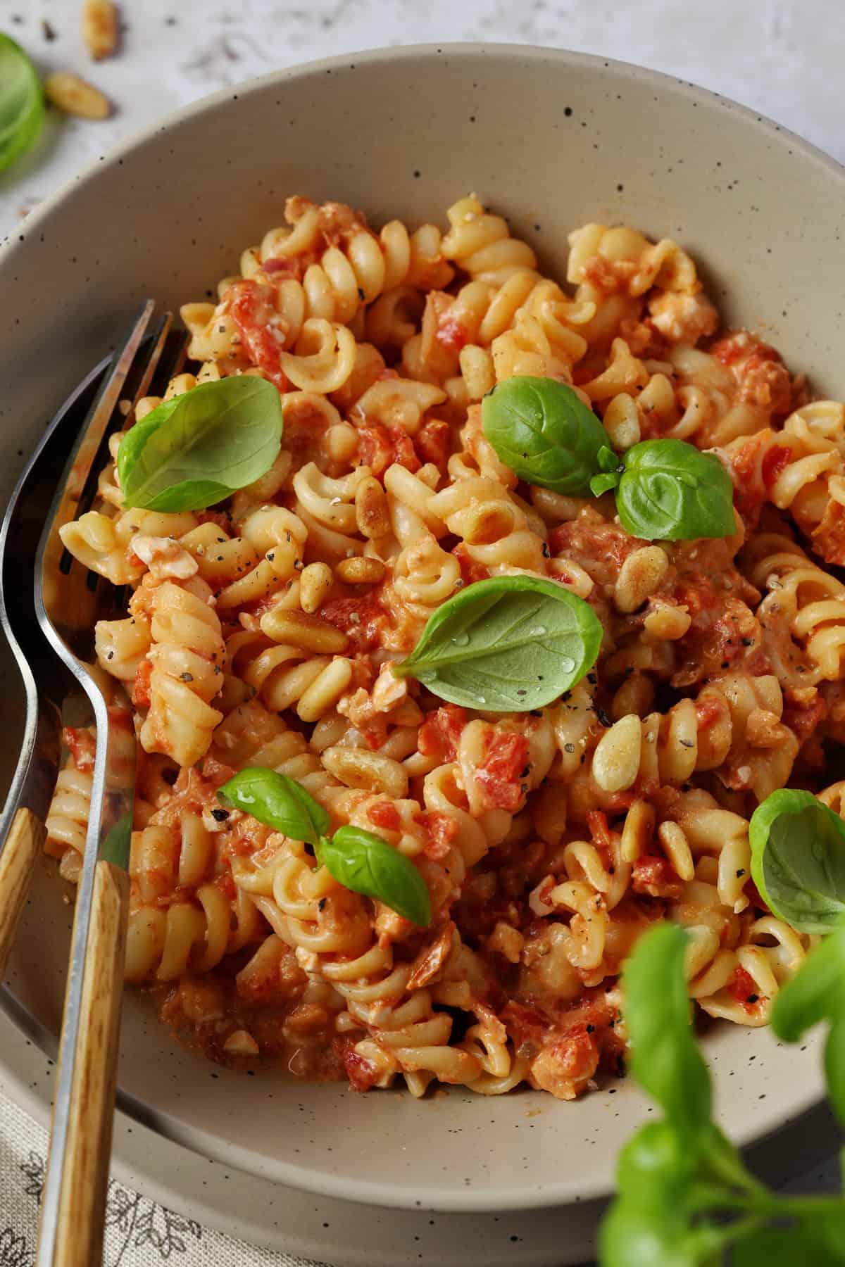 A close-up shot of a bowl of pasta tossed in a creamy roasted red pepper and feta sauce.