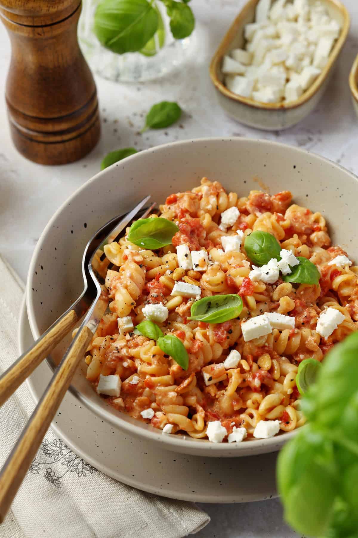 Close-up of a bowl of pasta with roasted red pepper feta sauce, topped with crumbled feta.