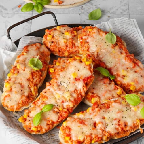 Eine runde, dunkle Servierplatte mit Pizzabrötchen.