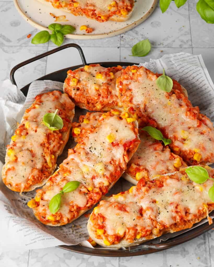 Eine runde, dunkle Servierplatte mit Pizzabrötchen.