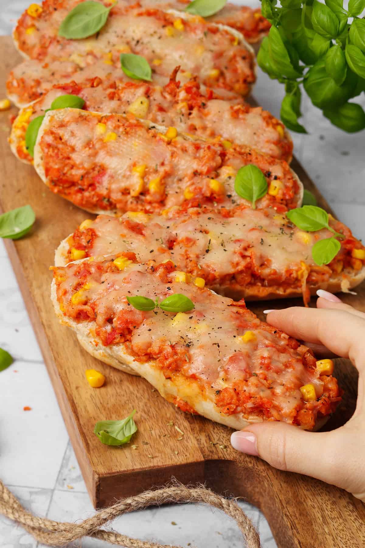 A rectangular wooden tray filled with baked pizza rolls.