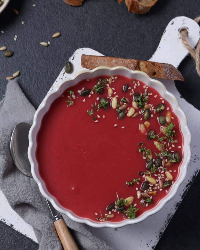 Eine Suppenschale mit Rote-Bete-Suppe, garniert mit Pinienkernen, Sonnenblumenkernen und Kresse.