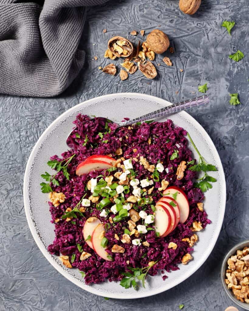 Ein heller Teller mit Rotkohlsalat mit Apfel, Walnüssen und Feta.