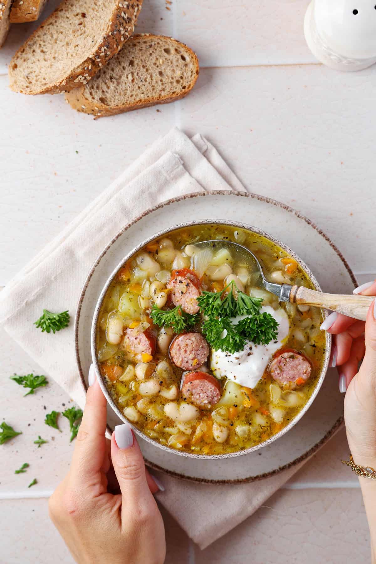 A soup bowl filled with white bean stew and smoked sausage.