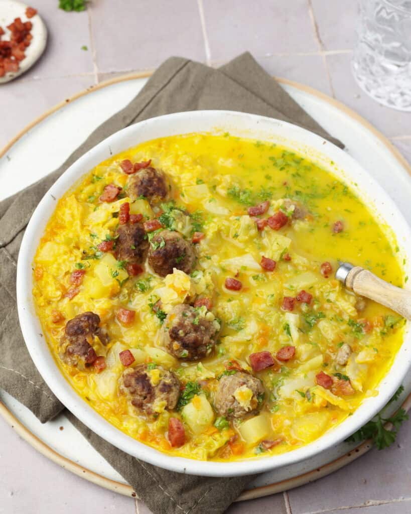 Ein Suppenteller mit Wirsingsuppe mit Hackbällchen.