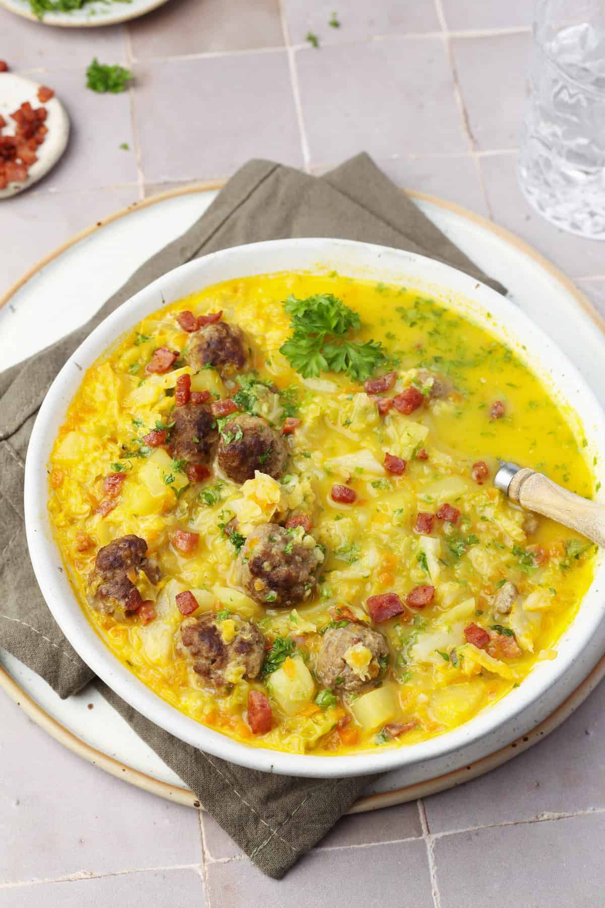 Ein Suppenteller mit Wirsingsuppe mit Hackbällchen.