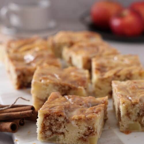 Mehrere Stücke Zimtschneckenkuchen mit Apfel auf einem Serviertablett.