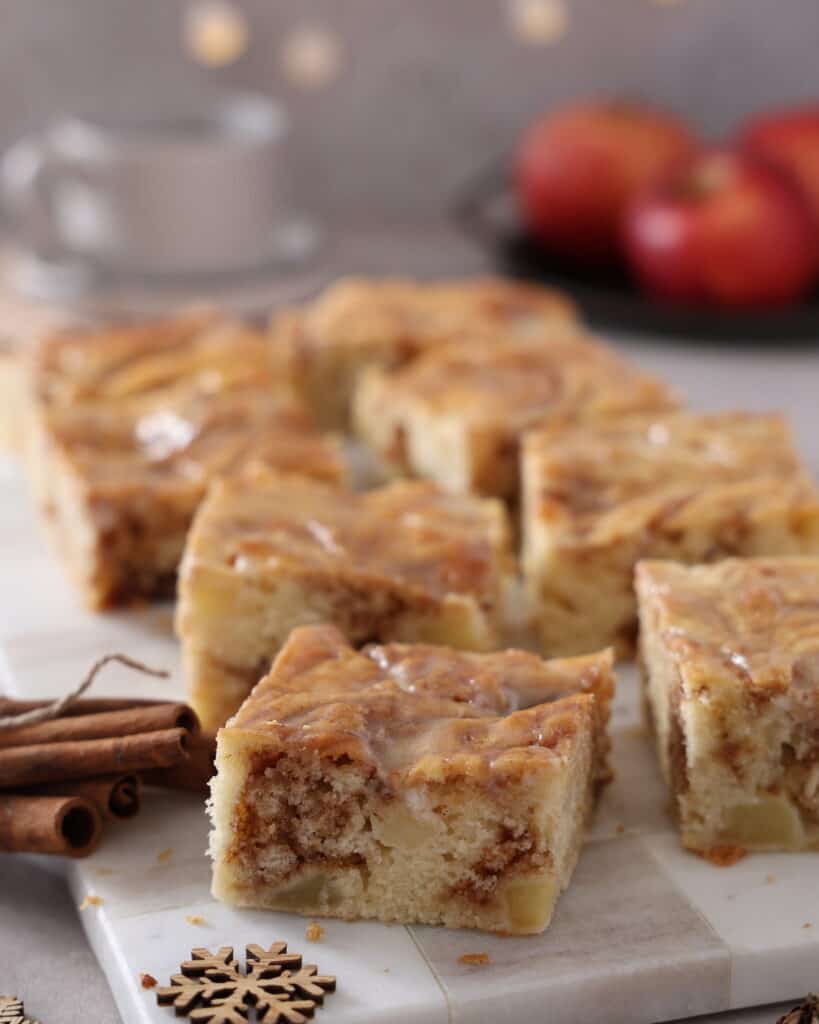 Mehrere Stücke Zimtschneckenkuchen mit Apfel auf einem Serviertablett.