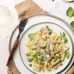 Ein Teller mit Zitronen-Rahm-Pasta mit Champignons & Erbsen.