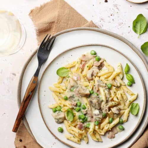 Ein Teller mit Zitronen-Rahm-Pasta mit Champignons & Erbsen.