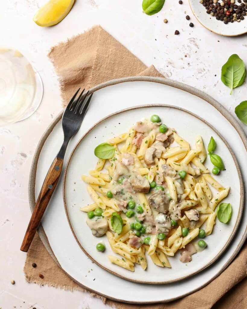 Ein Teller mit Zitronen-Rahm-Pasta mit Champignons & Erbsen.