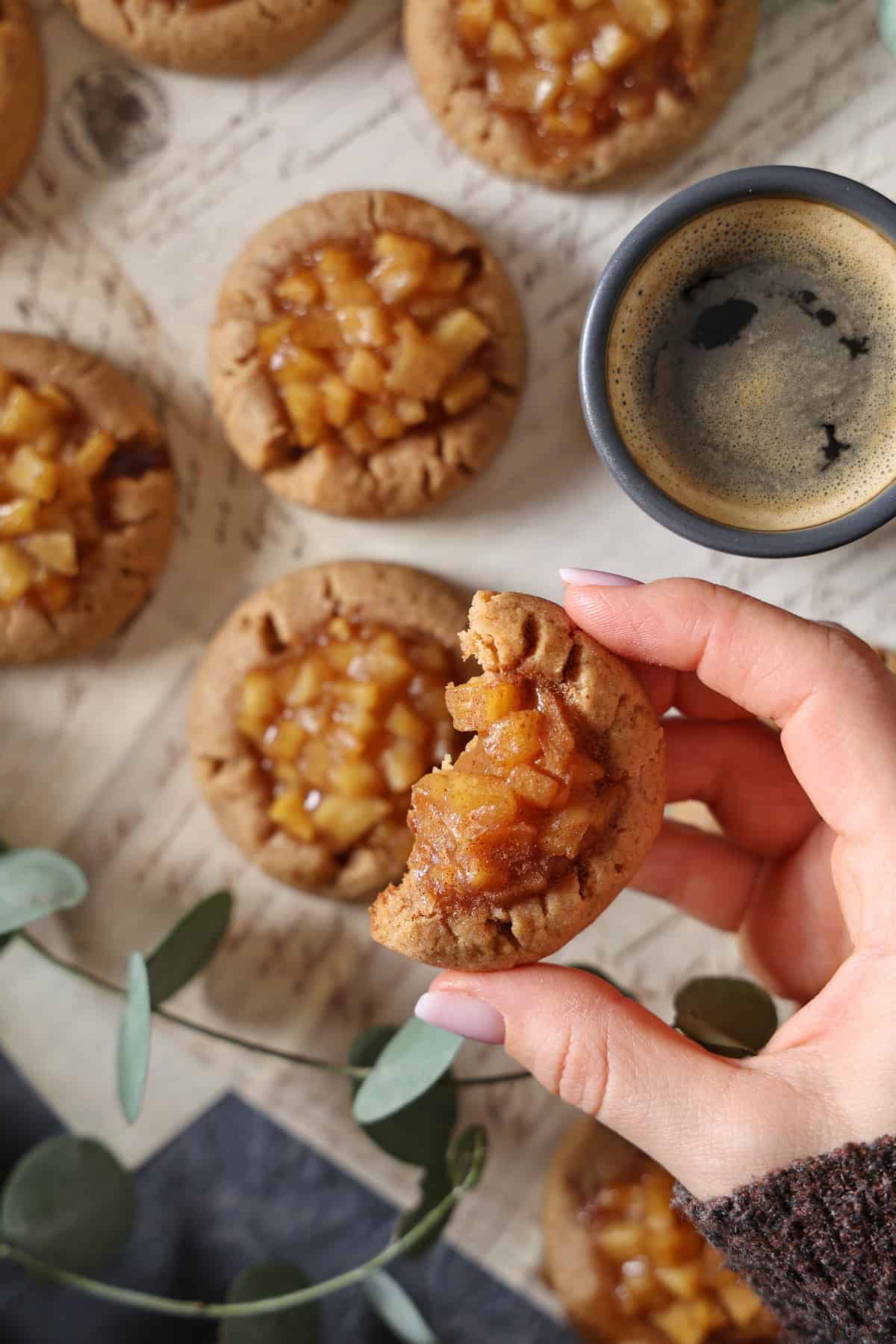 A hand holding a delicious apple cinnamon cookie with more cookies in the background.