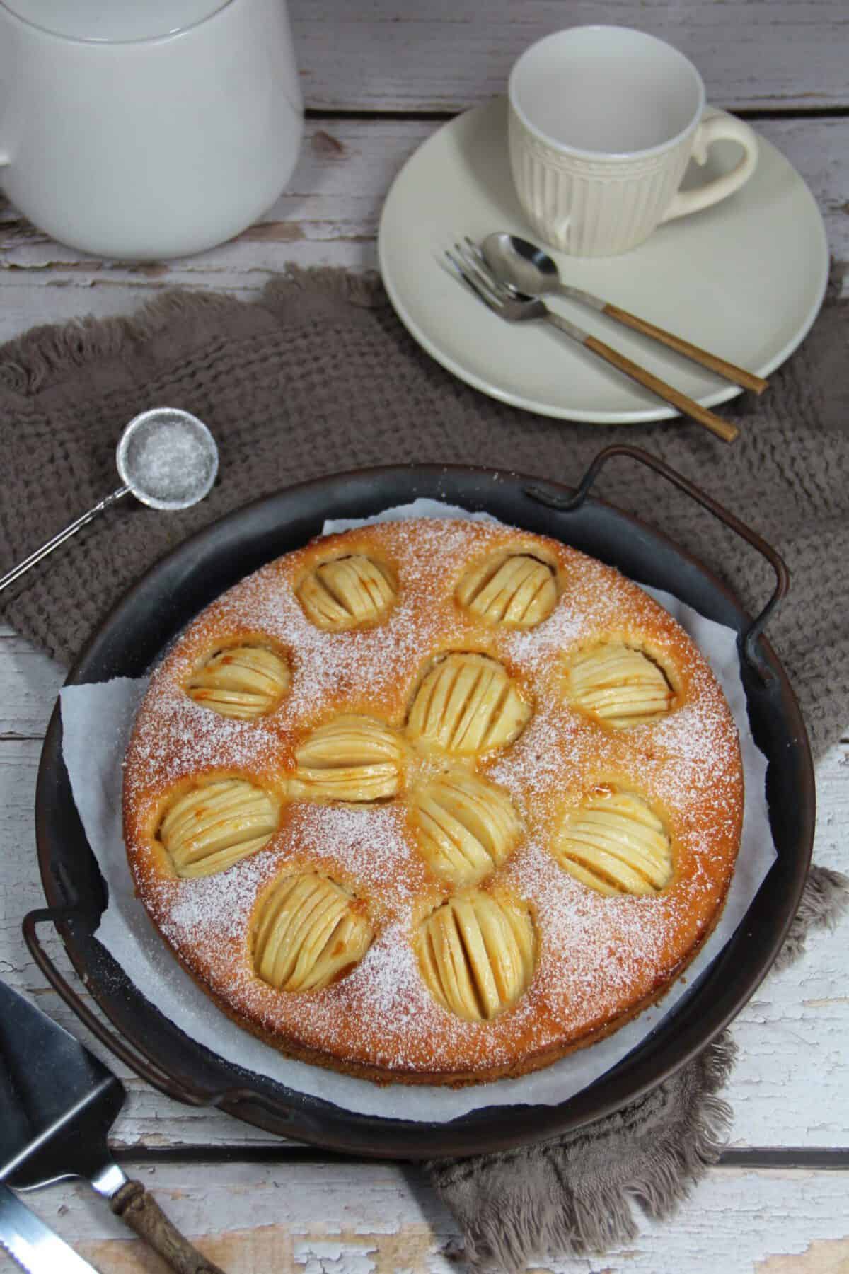 A whole apple cake on a metal serving tray.