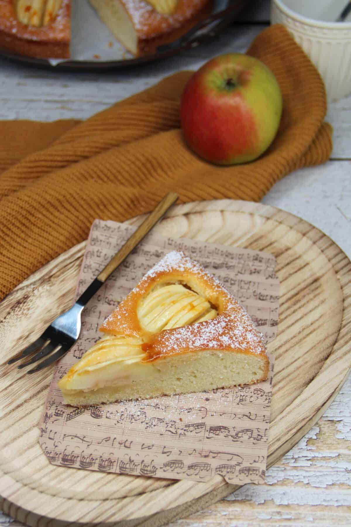 A slice of apple cake on a wooden board.