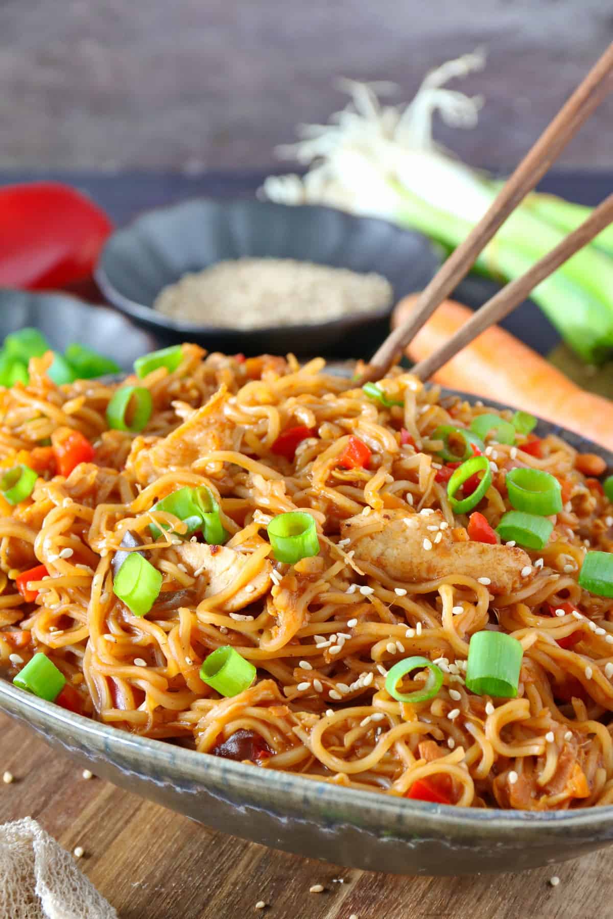 A bowl of Asian chicken noodles served with chopsticks.