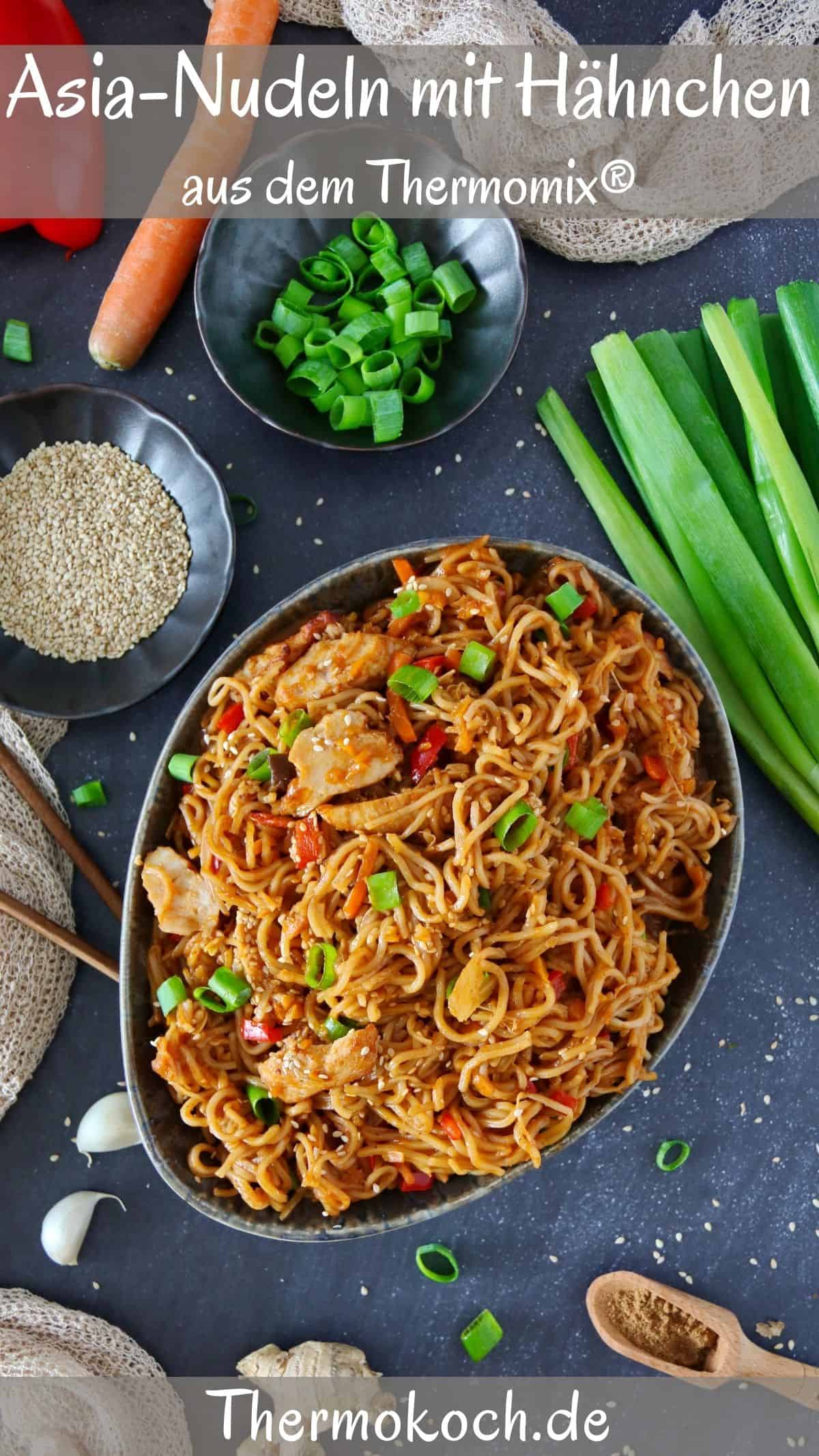 An oval serving bowl filled with Asian chicken noodles surrounded by garnish.