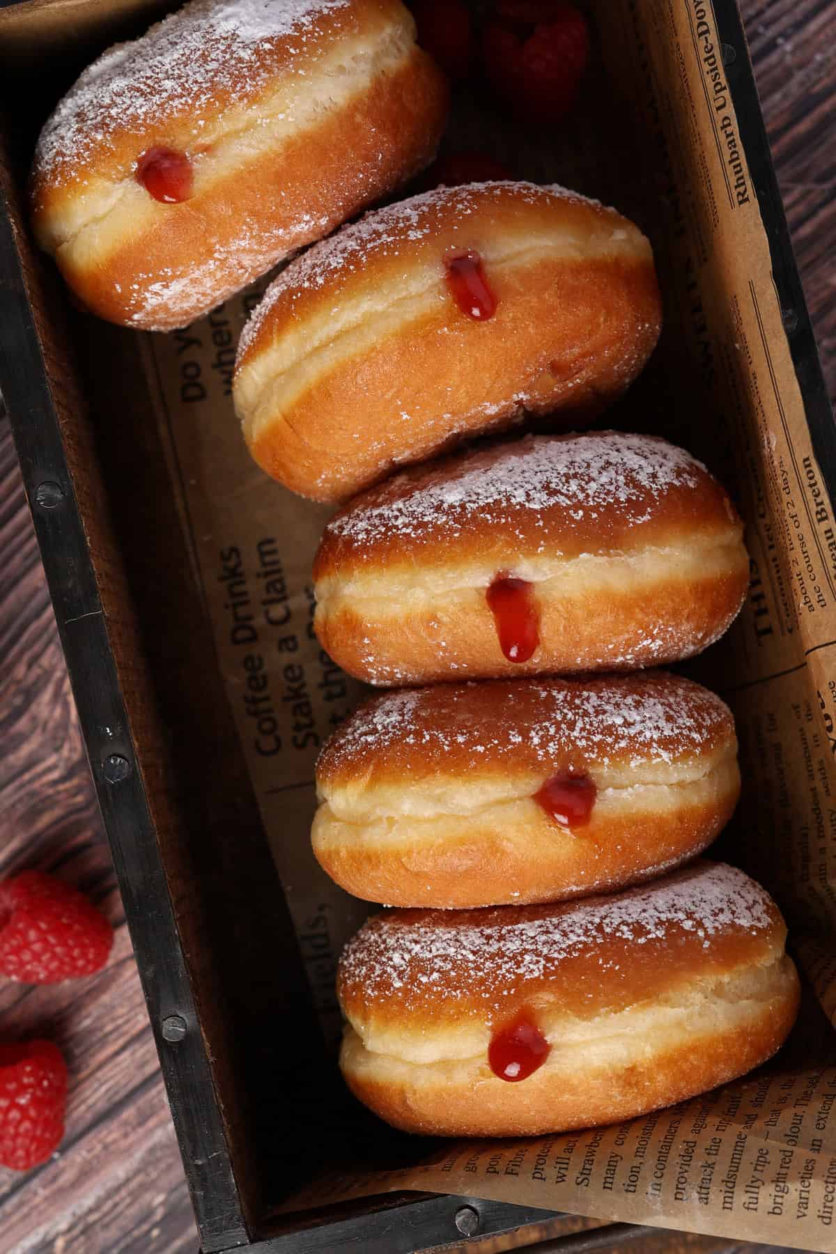 Several jelly donuts in a rectangular box.